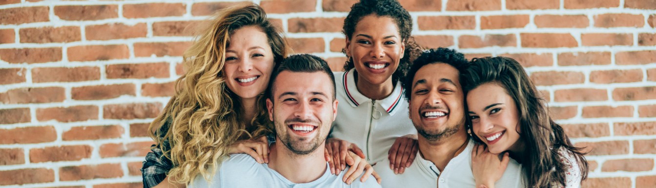 Gruppo di ragazzi e ragazze sorridenti davanti a un immobile, simbolo dei benefici del bonus affitto giovani 2025
