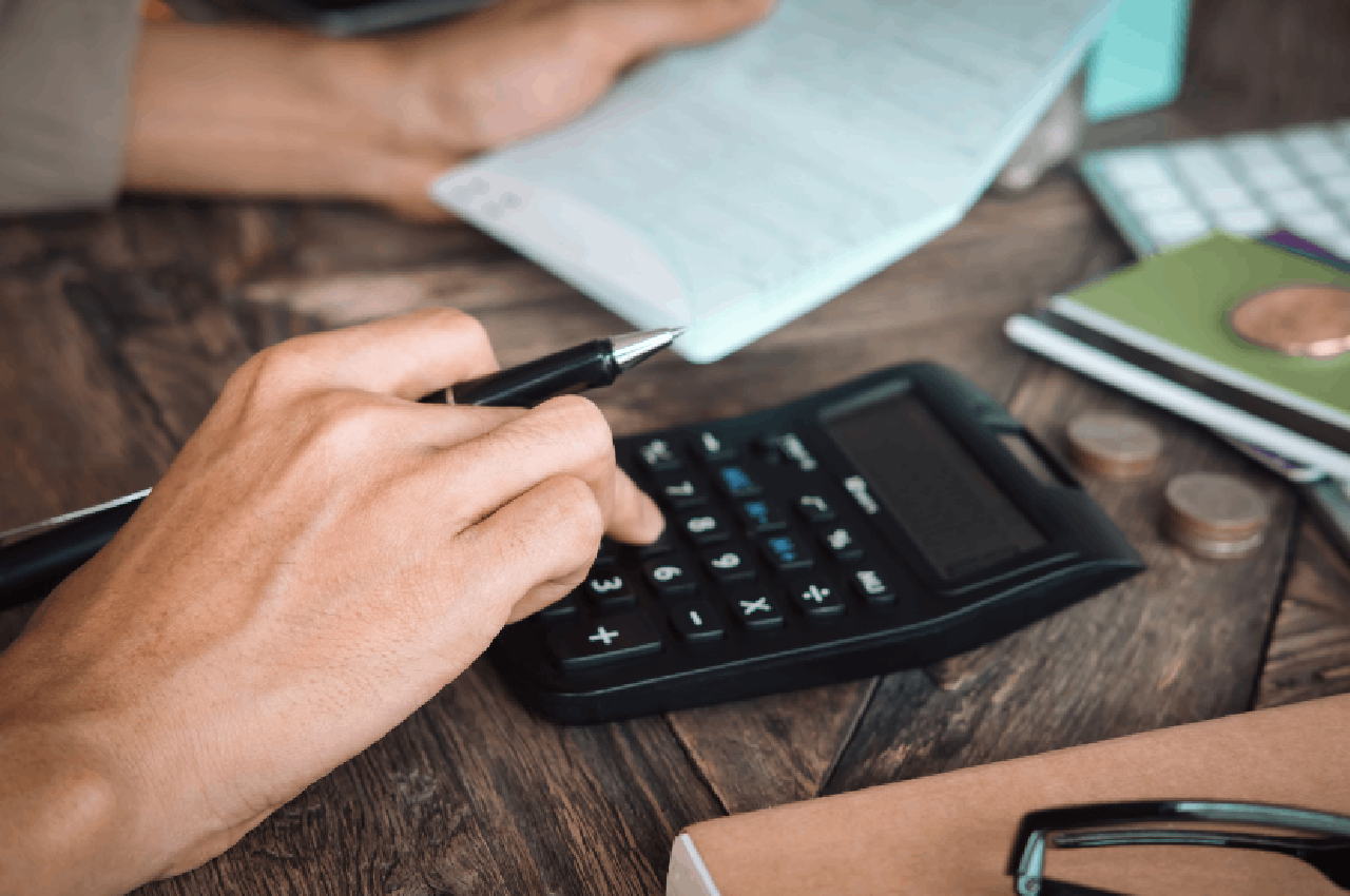 Mano che utilizza una calcolatrice su una scrivania per il calcolo dell’adeguamento ISTAT degli anni pregressi