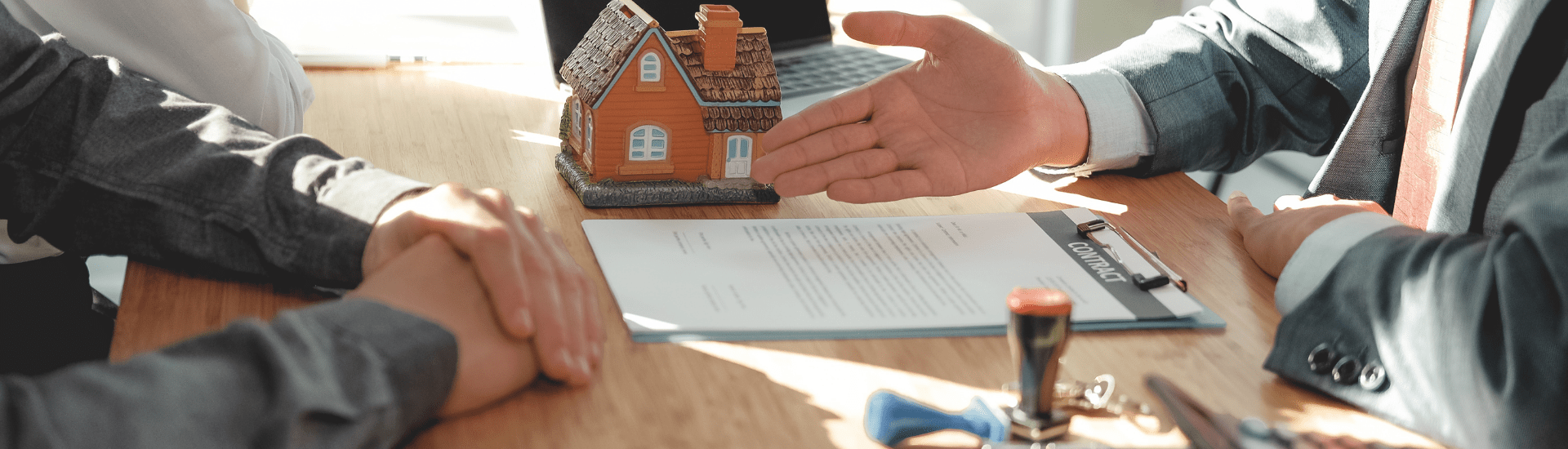 Scrivania con casa in miniatura e contratto di affitto, a simboleggiare il calcolo del canone di affitto