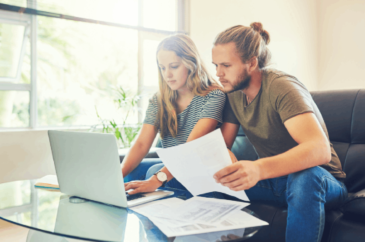 Coppia seduta davanti al computer mentre esamina documenti relativi a un contratto di locazione a canone concordato.