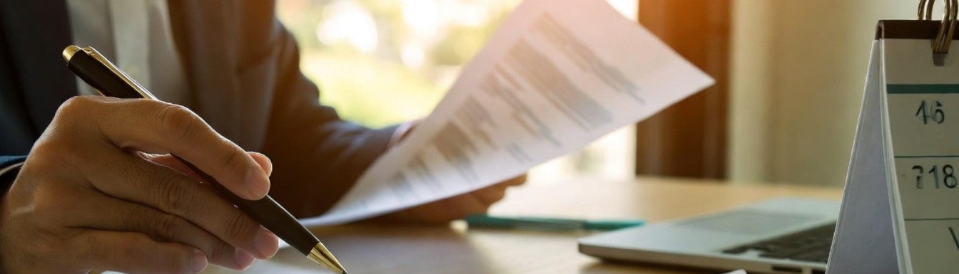 Mani che tengono una penna e un documento, simbolo della redazione di una lettera di sfratto per morosità.