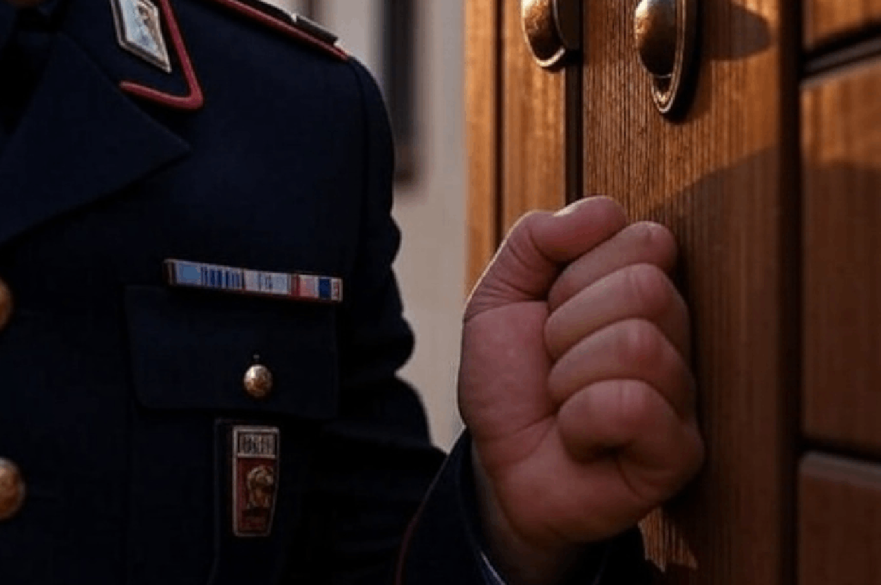 Ufficiale giudiziario in divisa che bussa alla porta di un’abitazione durante uno sfratto esecutivo.