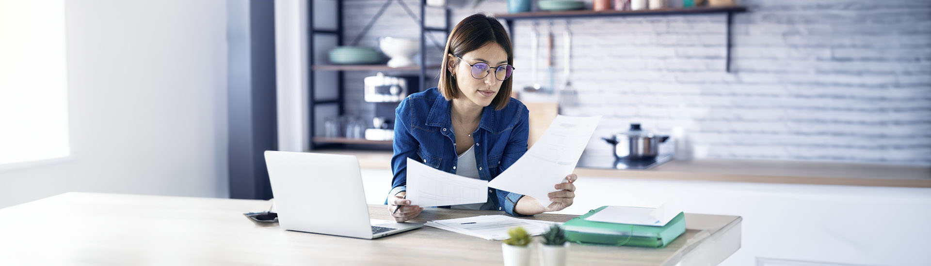 Persona analizza documenti immobiliari sul tavolo di casa, contesto legato alla gestione di un immobile e ad affittare casa con mutuo