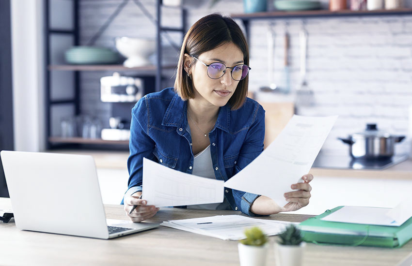 Persona controlla documenti immobiliari, per valutare come affittare casa con mutuo