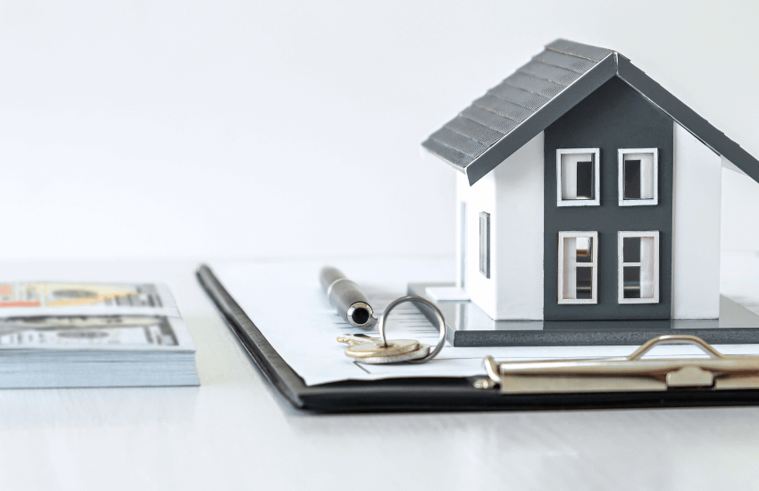 Scrivania con sopra un contratto di affitto e la miniatura di una casa, rappresentazione visiva dell’affitto garantito