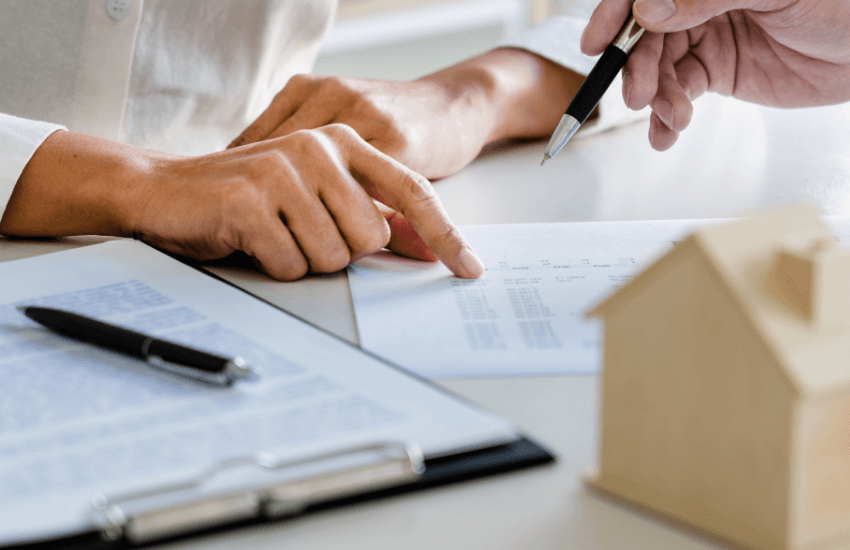 Due persone discutono un contratto di locazione, primo piano sulle mani sulla scrivania durante la cessione del contratto di locazione