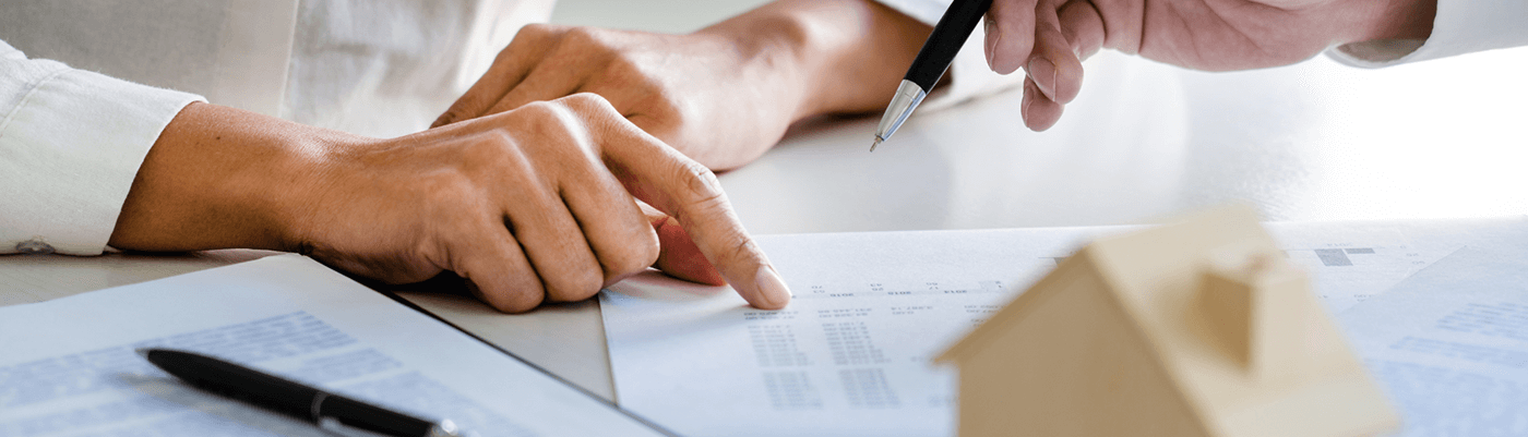 Primo piano delle mani di due persone a una scrivania mentre una indica un contratto, concetto di cessione del contratto di locazione