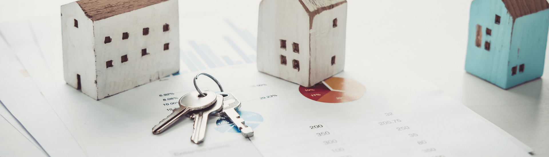 Tre miniature di case e chiavi su un tavolo, simbolo di disdetta del contratto d’affitto e gestione immobiliare 