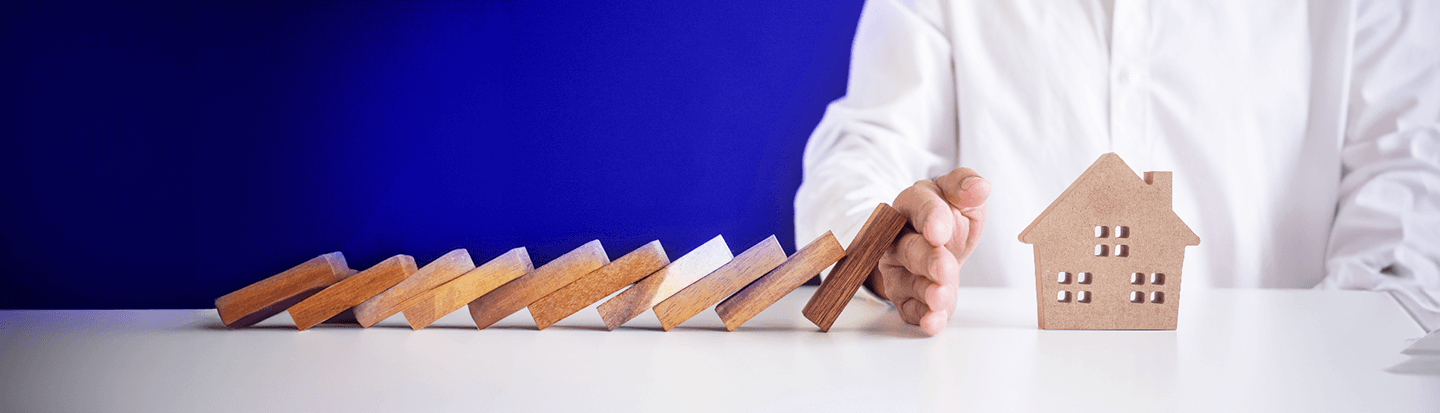 Mano che protegge il modello di una casa, simboleggiando la sicurezza della fideiussione bancaria per l’affitto