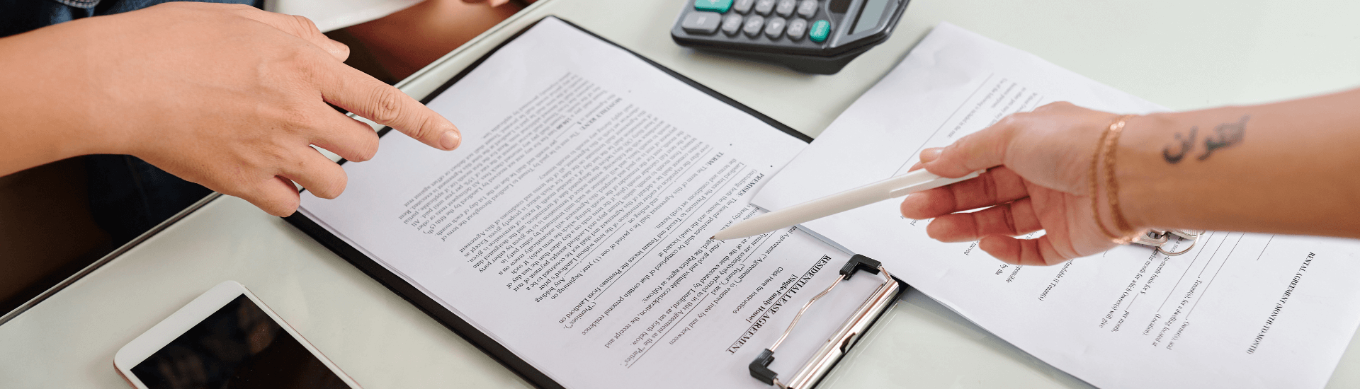 Mano che porge una penna per firmare la risoluzione del contratto di locazione tra locatore e conduttore