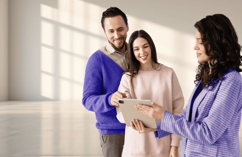 Coppia di proprietari di casa che parla con un agente immobiliare che mostra un annuncio su un tablet, a rappresentare la ricerca di un inquilino affidabile