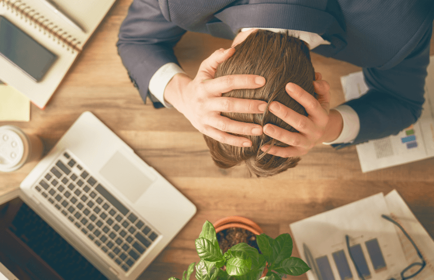 Uomo preoccupato con le mani tra i capelli seduto a una scrivania, simbolo dei rischi legati a un contratto di affitto transitorio